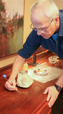 Wood conservation efforts, such as touching up finishes on the black walnut veneer of the guest house desk, occur each winter.