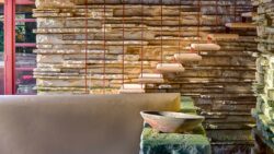 Stone exterior wall and floating concrete steps to the east terrace of the Fallingwater house with plung pool wall and short, wide bowl in the foreground, photographed by Andrew Pielage