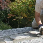 A worker repairs the grout atop one of the stone walls of the main house at Fallingwater.
