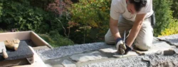A worker repairs the grout atop one of the stone walls of the main house at Fallingwater.