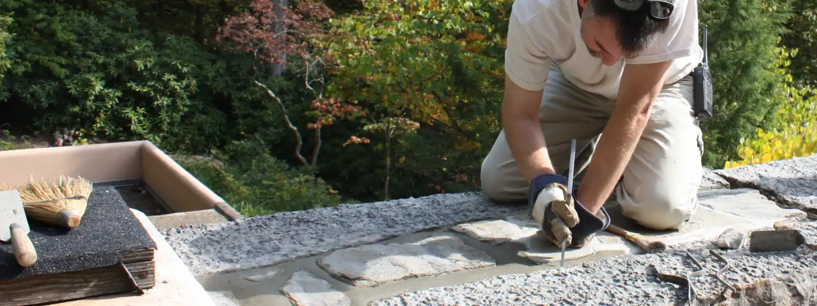 A worker repairs the grout atop one of the stone walls of the main house at Fallingwater.