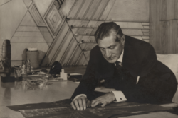 A black and white photograph shows Edgar Kaufmann Sr. leaning over his desk in his Frank Lloyd Wright designed office at his department store in downtown Pittsburgh.