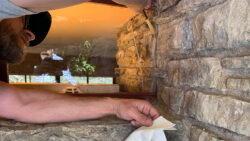 Silicone sealant is applied into a mortar joint where glass sets into the exterior stone wall.