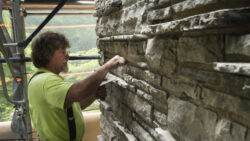 A Graciano masonry team member repoints mortar on the chimney outside of the Guest House.