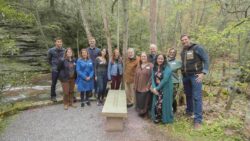 George Longenecker and many of his past interns pose at the stone bench along Bear Run that was dedicated in spring 2023 in recognition of his contributions to Fallingwater.