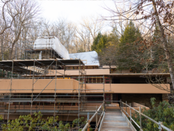 A long scaffolding bridge extends towards Fallingwater.