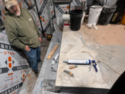 A man in a small room squares up concrete on a crucial part of Fallingwater.