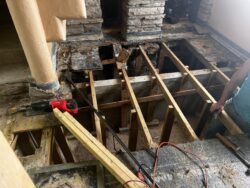 Detail shot of Sr.'s Terrace Demolition. Wooden beams are exposed and a worker is working.